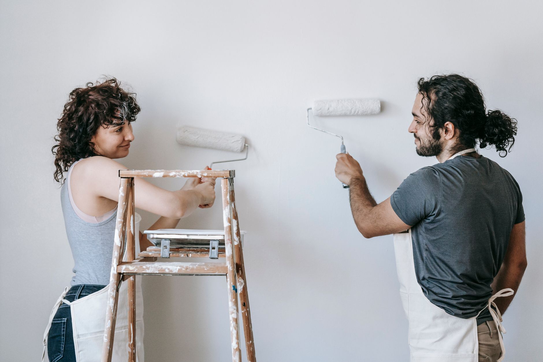 A painter rolling a light coat onto a wall